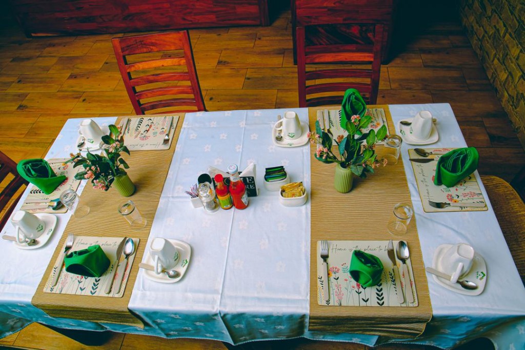Dining tables set with green napkins and Home Bliss tableware