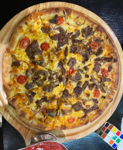 Wood-fired style pizza with grilled meat and fresh tomatoes